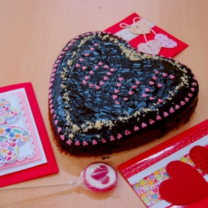 Walentynkowe przedmioty w postaci kartki, lizaka i ciasta z wykorzystaniem serc.